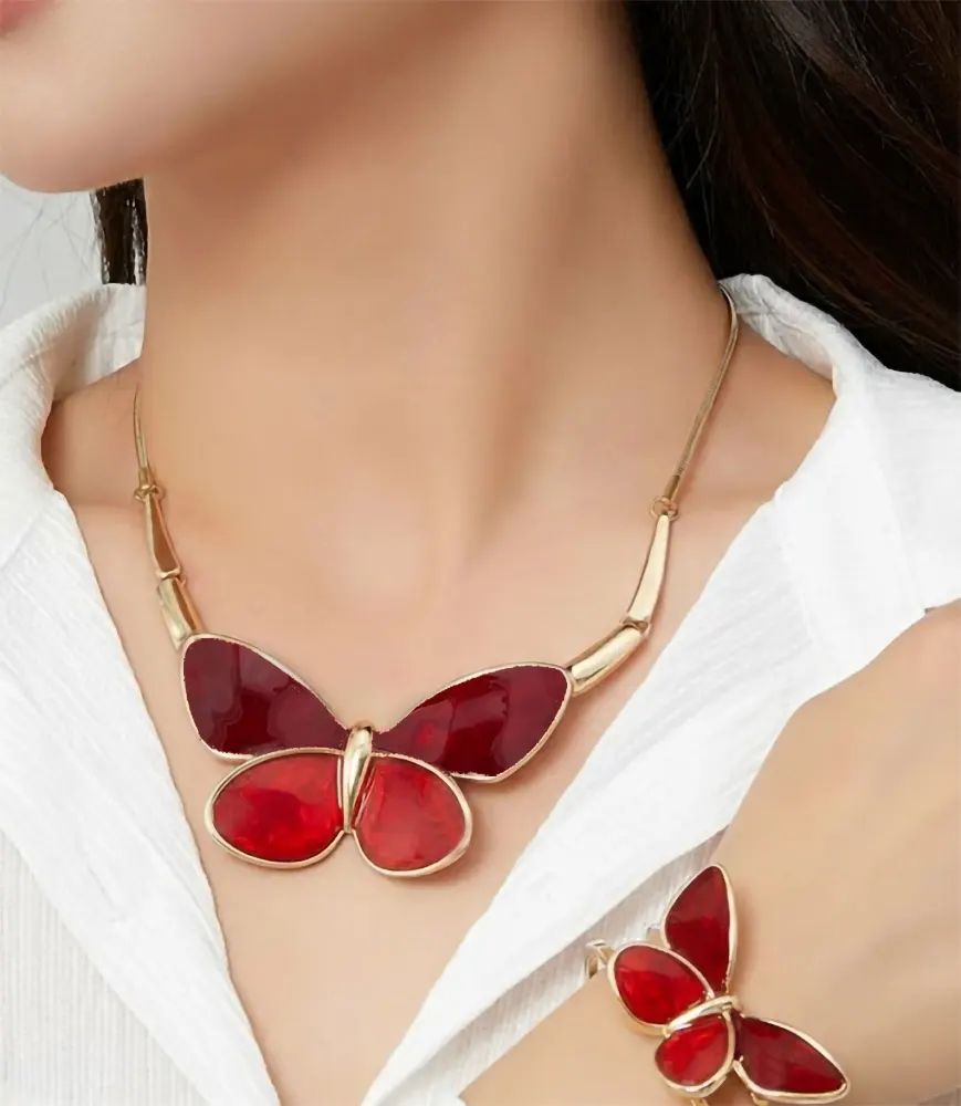 Woman wearing Belle Miss ALBINENN rigid bracelet with golden structure and large red butterfly motif made of resin. Jewelry gift Cyprus.