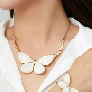 Woman wearing Belle Miss ALBINENN gold necklace with large white resin butterfly. Jewelry gift Cyprus.
