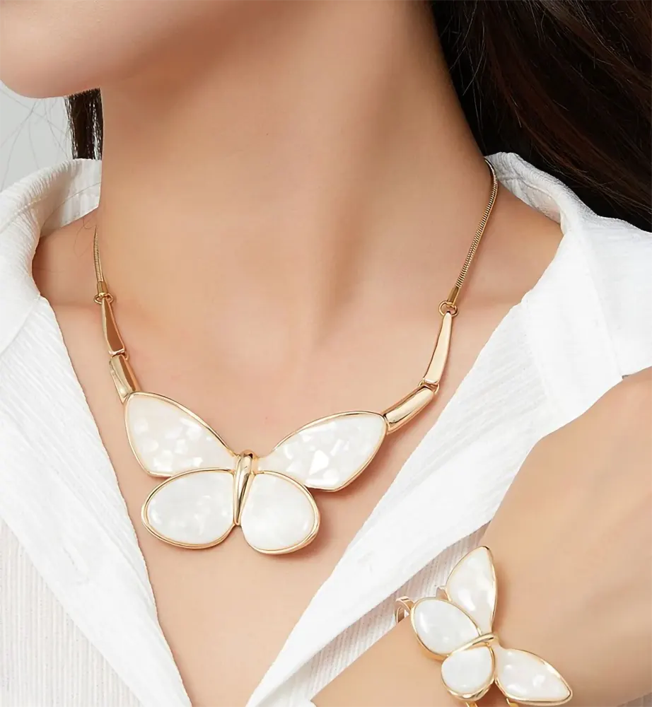 Woman wearing Belle Miss ALBINENN gold necklace with large white resin butterfly. Jewelry gift Cyprus.